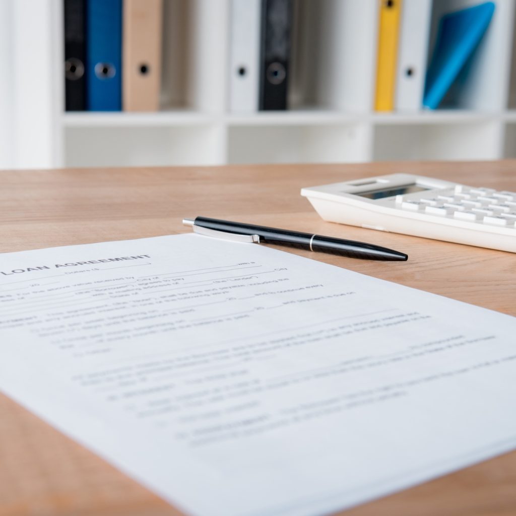 loan agreement, pen and calculator on wooden table in office